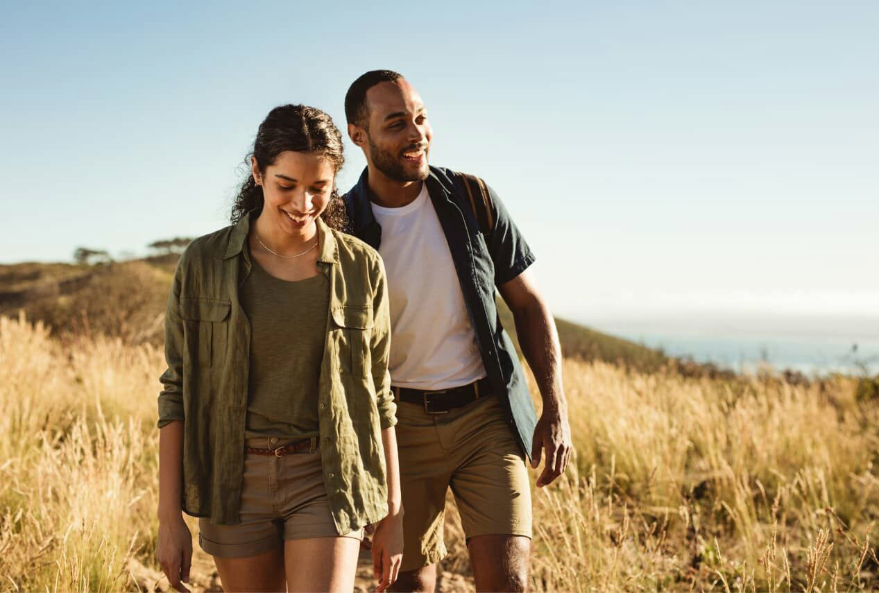 A couple strolling through brush while on Safari.