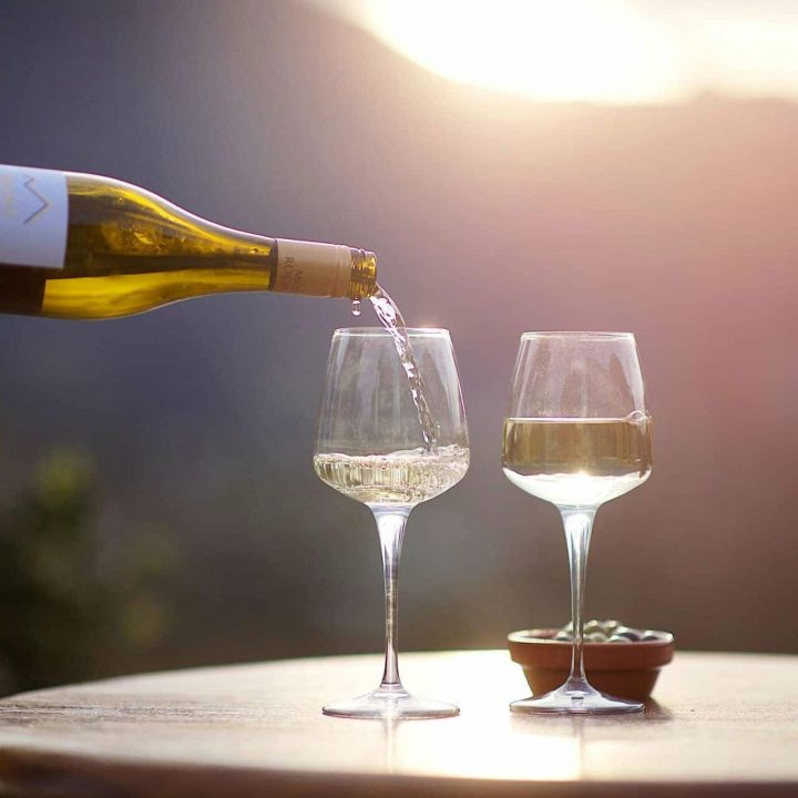 Two glasses of wine being poured in the sunshine.