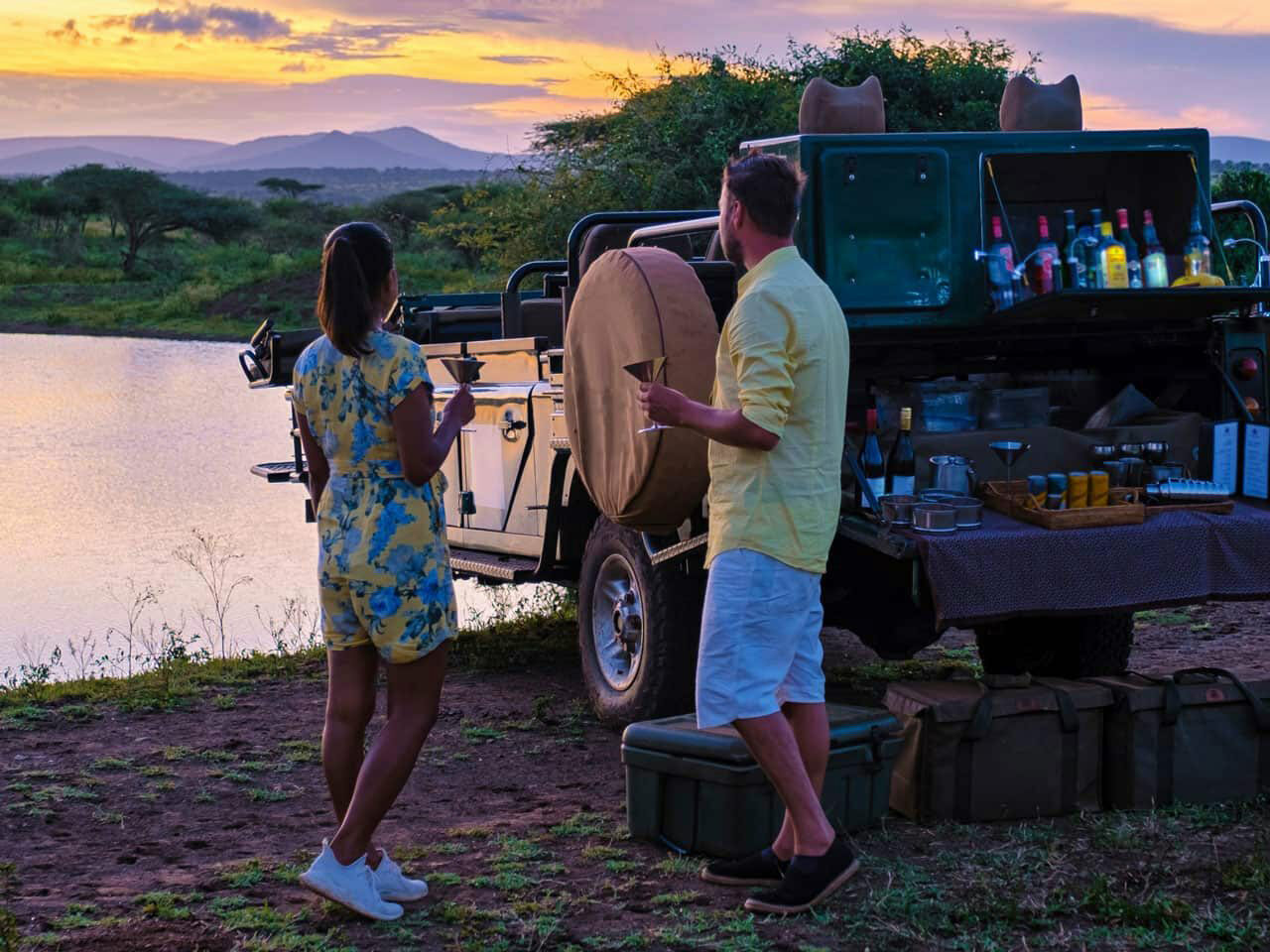 A woman and a man enjoying a cocktail while on safari.