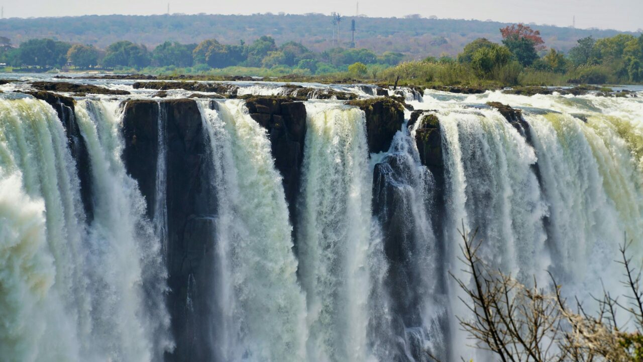 The curtain of Victoria Falls cascades in several white streams along the cliff edge, Zimbabwe, on an African safari holiday.