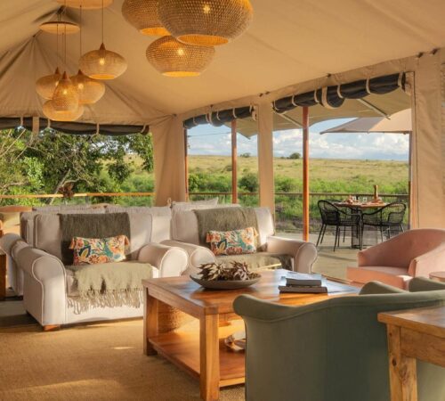 Spacious tented lounge with sofas and a coffee table looking out to the plains, Rekero Camp, Kenya.