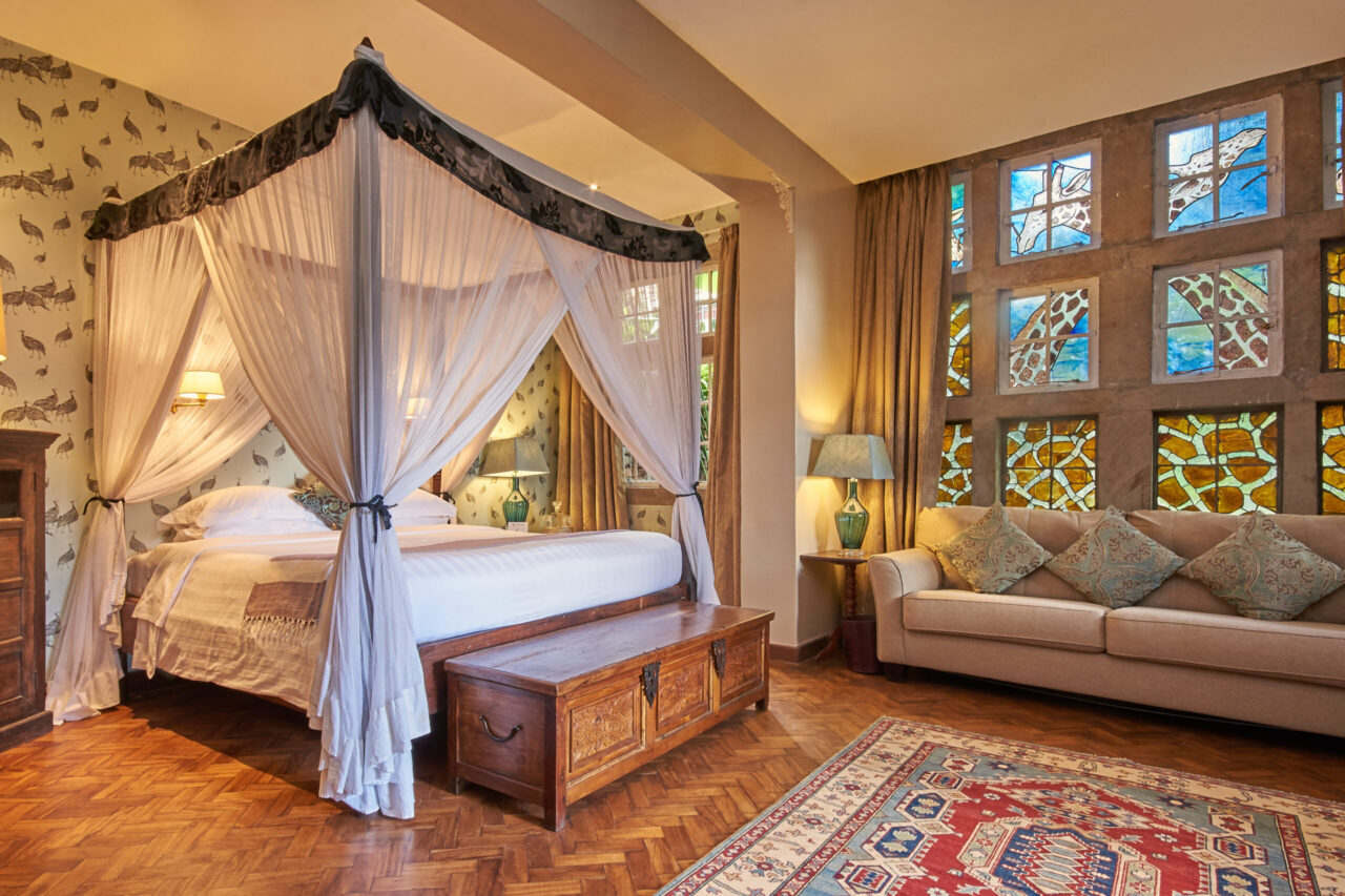 A bedroom with stained glass windows at Giraffe Manor, a luxury safari lodge, Kenya.