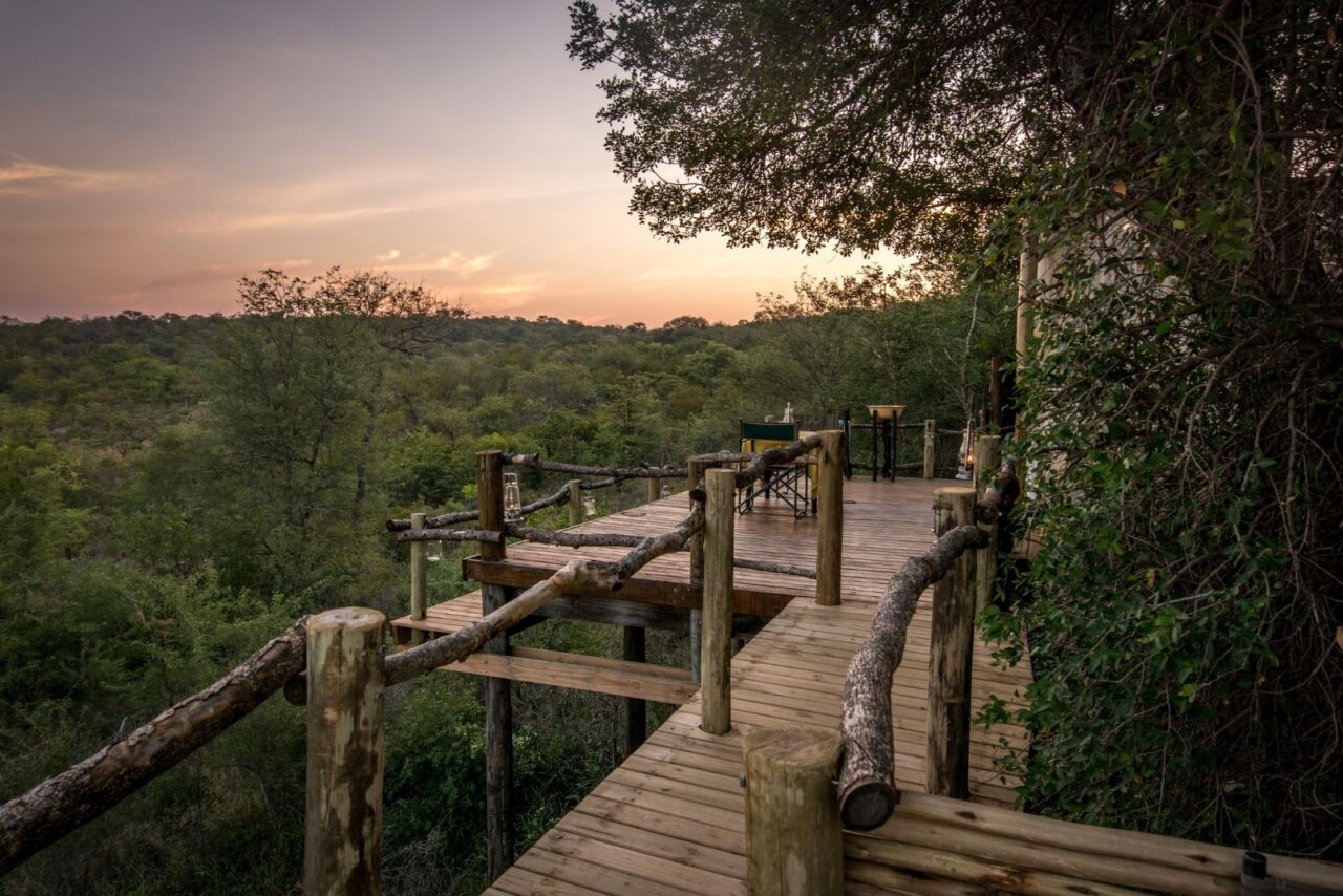 Wooden decking frames the sleep-out platform at this luxury safari camp, set among trees, Garonga, South Africa.